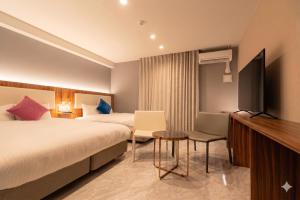 a hotel room with a bed and a flat screen tv at LIBERATED HOTEL Haruyoshi Kaichi in Fukuoka