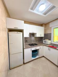 a kitchen with white cabinets and a refrigerator at Visit Chamal - Palmera 4 in Oued Laou