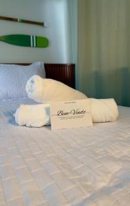 a sign sitting on top of a bed with towels at Loft Duplex Moderno - 50m da Praia - Ar - Wi-Fi in Salinas da Margarida