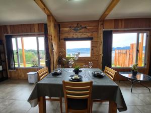 a dining room with a table and chairs and windows at Cabañas Dos Maitenes in Villa Traful