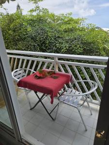 a table and chairs on a balcony with a red blanket at Le Nid Créole in Belle-Allée +26 photos