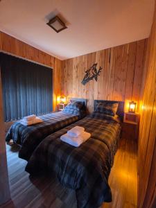 two beds in a room with wood paneled walls at Cabañas Dos Maitenes in Villa Traful