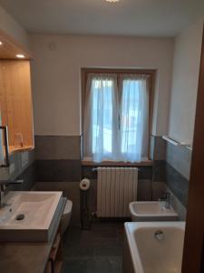 a bathroom with a sink and a toilet and a window at Chalet Bianco in Valdidentro +24 photos