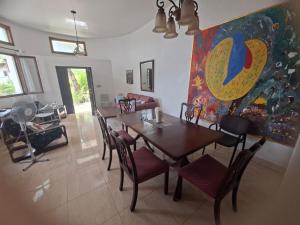 a dining room with a table and chairs and a painting at hebergement paradis Haiti in Petionville
