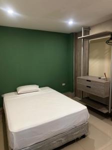 a bedroom with a white bed and a green wall at La Rosita 2 in Puerto Colombia