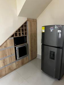 a kitchen with a black refrigerator and a wooden cabinet at La Rosita 2 in Puerto Colombia