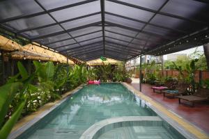 an indoor swimming pool with a roof with plants at Nọng Villa in Phan Thiet