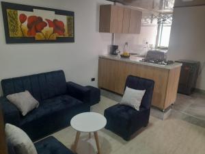 a living room with a couch and chairs and a kitchen at Alojamiento y Confort in Tunja