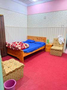 a bedroom with a bed and two chairs in it at Galiyat City hotel in Mingāora