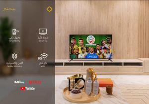 a room with a tv on a wall and a table at Amber Hospitality - Arrawdha in Riyadh