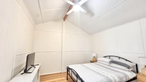 a white bedroom with a bed and a ceiling fan at JJ s Holiday House in Wooli