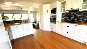 a kitchen with white cabinets and a hard wood floor at JJ s Holiday House in Wooli