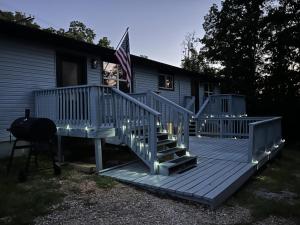 a deck with lights and a house with a flag at Bluebird Liberty Cottage in Saint Robert
