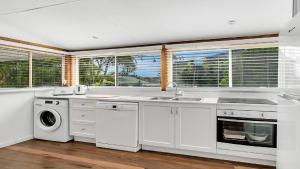 a white kitchen with a sink and a dishwasher at Tullenderly in Wooli