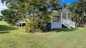 a white house with palm trees in front of it at Tullenderly in Wooli