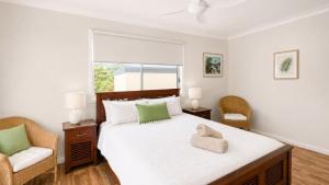 a bedroom with a large bed and two chairs at Surfside in Wooli