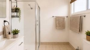 a white bathroom with a shower and a sink at Surfside in Wooli