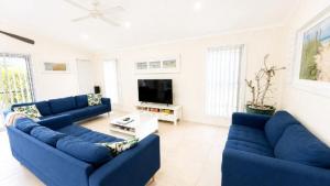 a living room with blue couches and a tv at Sandy Feet in Wooli