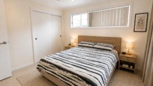 a bedroom with a bed with a striped comforter and a window at Sandy Feet in Wooli