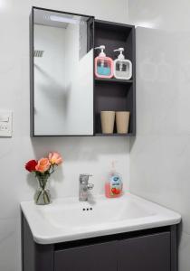 a bathroom sink with a vase of flowers and a mirror at LAN HA PEARL HOTEl in Cat Ba