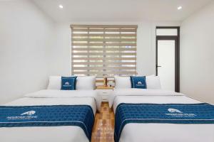 two beds in a room with blue and white at LAN HA PEARL HOTEl in Cat Ba