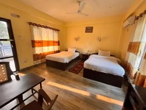a room with two beds and a table and a desk at silent park sauraha in Sauraha