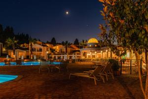 a resort with chairs and a pool at night at Olympion Village in Kavos