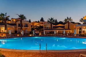 a swimming pool in front of a resort at night at Olympion Village in Kavos