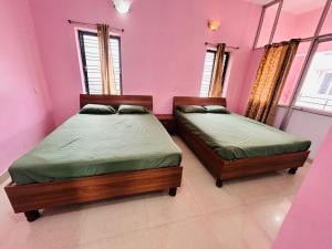 two beds in a room with pink walls and windows at Breezevalley Residency in Yelagiri