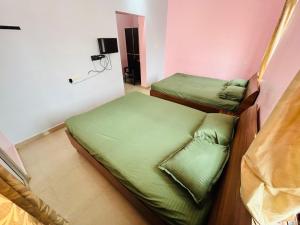 two beds in a room with green sheets at Breezevalley Residency in Yelagiri