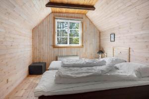 two beds in a room with wooden walls and a window at 0140-Romo-Kap-Farvel-7 in Høm