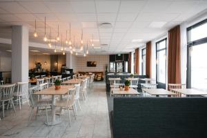 a dining room with tables and chairs and windows at Hotell Fyrislund in Uppsala