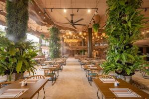 a restaurant with wooden tables and chairs and plants at Pamookkoo in Kata Beach