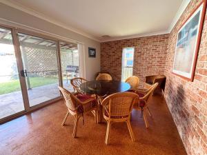 a dining room with a table and chairs and a brick wall at Parkview Lodge - Bring your own linen. in South West Rocks