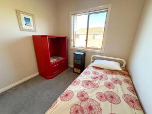 a bedroom with a bed and a red cabinet at Parkview Lodge - Bring your own linen. in South West Rocks