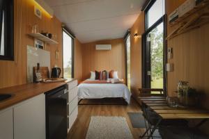 a bedroom with a bed and a kitchen with a table at Two-Ki by Tiny Away in Rainbow Flat