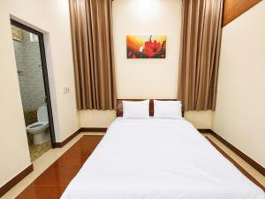 a bedroom with a large white bed and a toilet at The Mellow House Nhật Lệ in Dong Hoi +28 photos