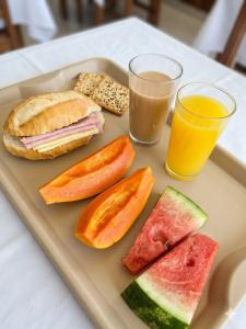 a tray of food with a sandwich and a glass of orange juice at Hotel 3 meninos in Itariri