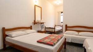 a bedroom with two beds and a mirror at Hotel 3 meninos in Itariri
