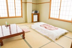 a room with a bed and a table and windows at 藤の湯えびす屋 in Yunokami