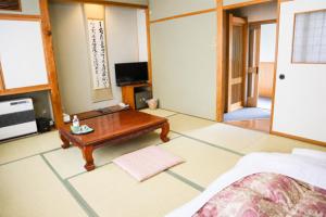 a living room with a coffee table and a tv at 藤の湯えびす屋 in Yunokami