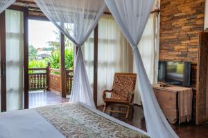a bedroom with a bed and a chair and a television at Aryaswara Villa Ubud in Ubud