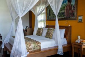 a bedroom with a bed with white drapes at Aryaswara Villa Ubud in Ubud