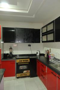 a kitchen with red cabinets and a stove top oven at Maison Madame - Female only Shared Apartment Lekki in Lekki