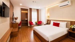 a bedroom with a white bed and red chairs at Le Centre Pleiku Hotel in Pleiku
