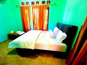 a bedroom with a bed with an orange curtain at Novena bungalow Oeseli in Pulau Helihana