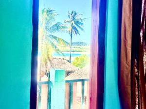 a view from a window of a beach with palm trees at Novena bungalow Oeseli in Pulau Helihana