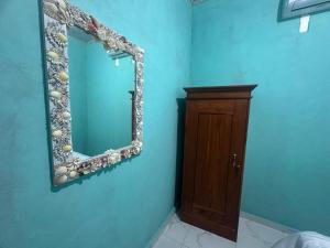 a bathroom with a mirror and a wooden cabinet at Novena bungalow Oeseli in Pulau Helihana +2 photos