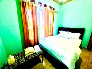 a green room with a bed and a window at Novena bungalow Oeseli in Pulau Helihana