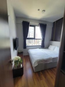 a bedroom with a bed and a window with blue curtains at Căn Hộ Cao Cấp Cara River Park in Cái Răng